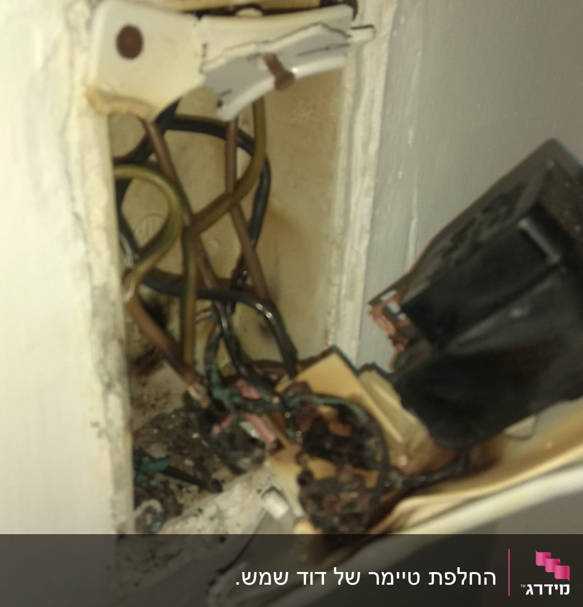 חוטי חשמל חשופים בקופסת חיבורים בקיר